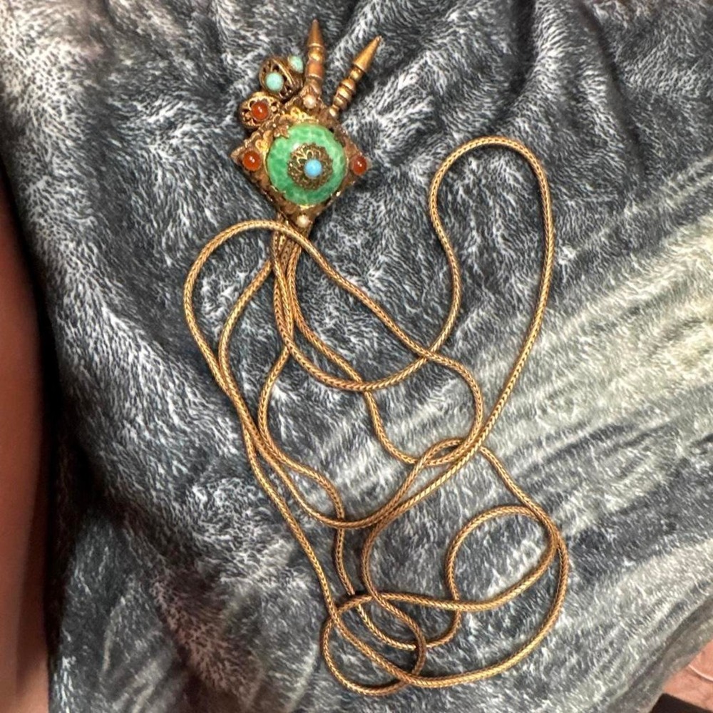 Multi-colored pendant necklace with green central stone surrounded by orange
